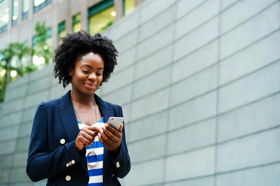 woman social media expert walking in front of building looking at her phone